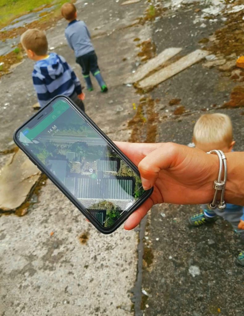 Geocachen im Geiseltalsee, Blick auf das Handy, kinder im Hintergrund