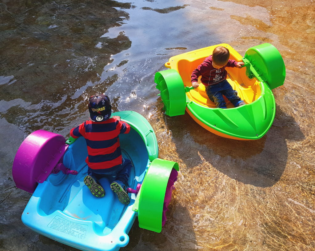 Die Kinder fahren auf dem Wasser mit kleinen Booten