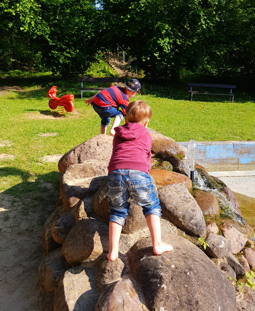 Die Kinder klettern auf den Steinen am Wasserbecken 