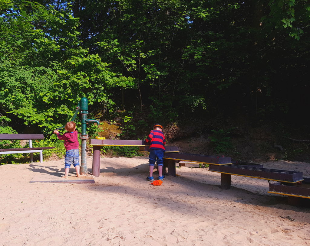 Die Kinder pumpen Wasser an der Goldwaschanlage im Spielpark