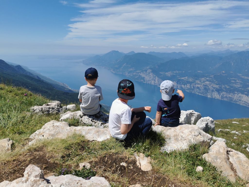 die Kinder sitzen auf dem Monte Baldo und schauen auf den Gardasee