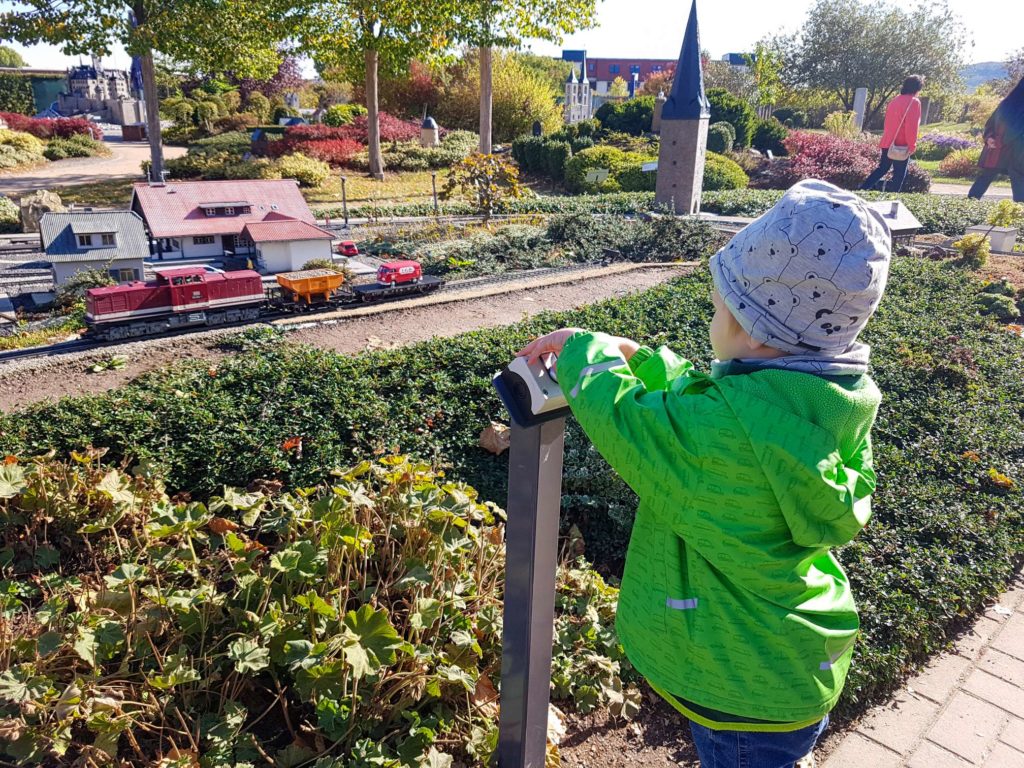 Kind drückt den Knopf zur Aktivierung der Modell-Dampflok im Miniaturenpark in Wernigerode im Harz, toller Ausflug für Kinder im Harz