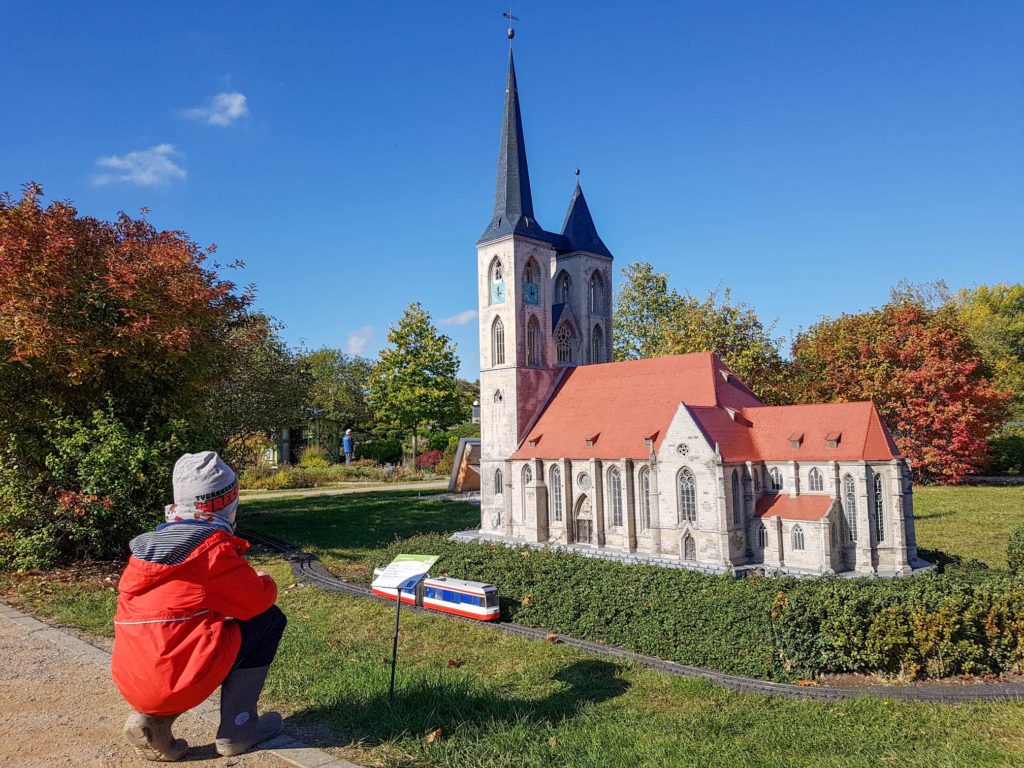 Ausflug für Familien im Harz, Miniaturenpark Wernigerode, Kind hockt vor dem Modell einer Kirche