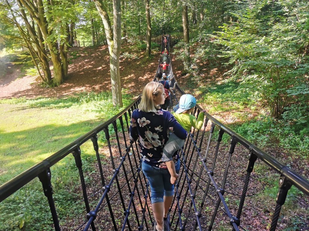 Mama läuft mit Kind über Hängebrücke im Barfußpark